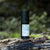 Product shot of ReGlow – Face Serum standing on a moss covered tree trunk
